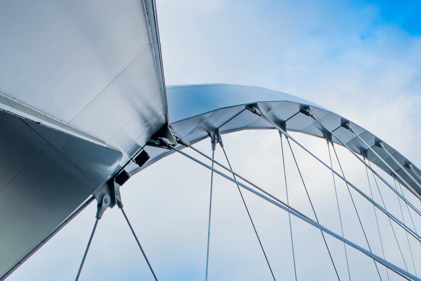 Modern bridge with metal arches and tension cables against the sky.